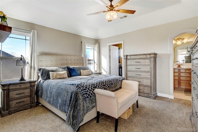 bedroom featuring light colored carpet, arched walkways, a ceiling fan, connected bathroom, and baseboards