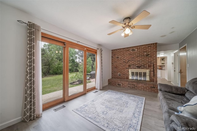 2276 S Dover Way, Lakewood, CO 80227 - living room with ceiling fan, wood finished floors, a brick fireplace, and baseboards