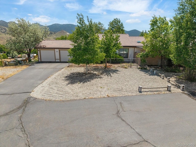 534 Crestone Ave, Salida, CO 81201 - obstructed view of property with a tiled roof, asphalt driveway, a mountain view, an attached garage, and stucco siding