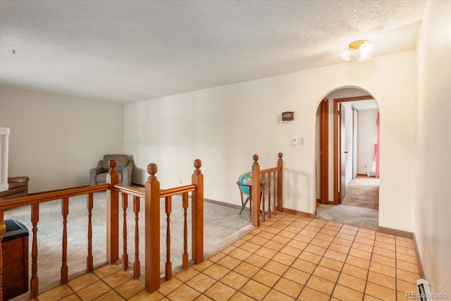 534 Crestone Ave, Salida, CO 81201 - hall with an upstairs landing, arched walkways, a textured ceiling, light colored carpet, and light tile patterned floors