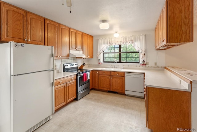 534 Crestone Ave, Salida, CO 81201 - kitchen with white appliances, under cabinet range hood, brown cabinets, light countertops, and light flooring