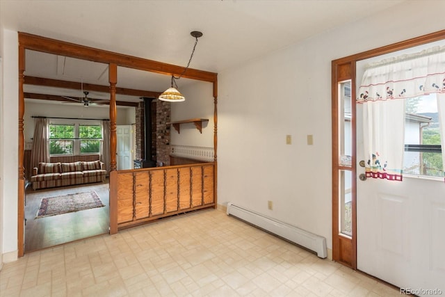 534 Crestone Ave, Salida, CO 81201 - unfurnished dining area featuring a baseboard heating unit, a wood stove, beamed ceiling, and a ceiling fan