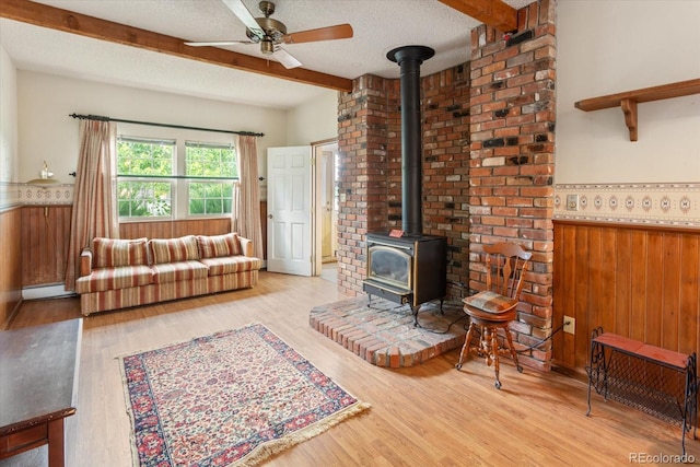 534 Crestone Ave, Salida, CO 81201 - living area featuring a wood stove, beamed ceiling, ceiling fan, light wood finished floors, and wainscoting