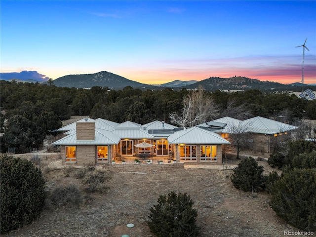 back of property at dusk with covered porch, metal roof, a standing seam roof, and a mountain view