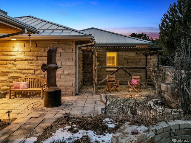 rear view of house with stone siding, a standing seam roof, and metal roof