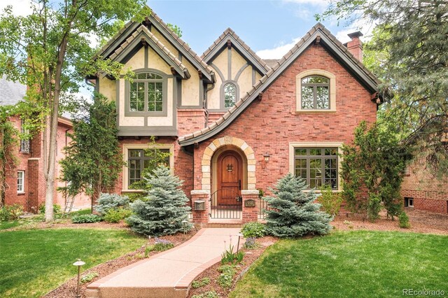 958 S Columbine St, Denver, CO 80209 - english style home featuring a front yard, a chimney, stucco siding, and brick siding