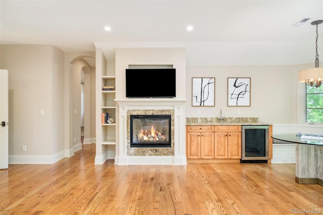 958 S Columbine St, Denver, CO 80209 - unfurnished living room with beverage cooler, arched walkways, a glass covered fireplace, light wood finished floors, and a chandelier
