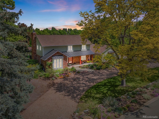 1579 W Costilla Pl, Littleton, CO 80120 - view of front of property with a chimney, covered porch, a standing seam roof, driveway, and roof with shingles