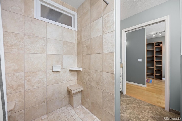 1579 W Costilla Pl, Littleton, CO 80120 - bathroom with tiled shower, track lighting, a walk in closet, and a textured ceiling
