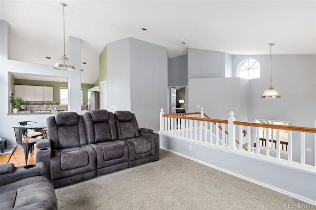 carpeted living room featuring high vaulted ceiling, baseboards, and plenty of natural light