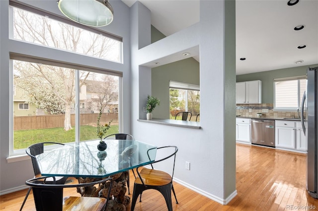 dining space featuring recessed lighting, a wealth of natural light, light wood-type flooring, and baseboards