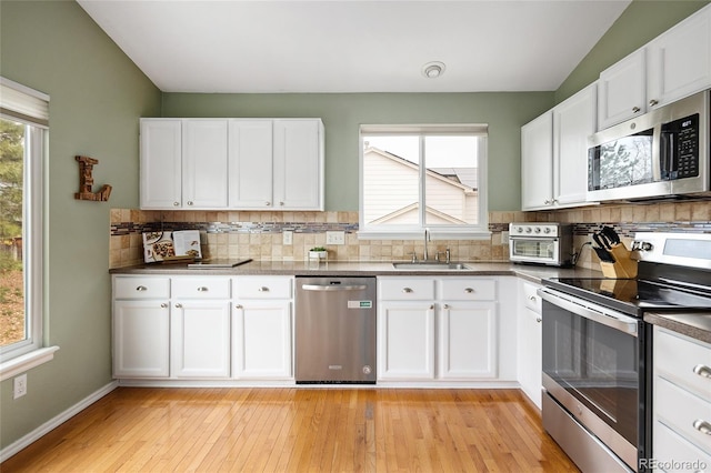 kitchen with appliances with stainless steel finishes, decorative backsplash, a sink, and a healthy amount of sunlight
