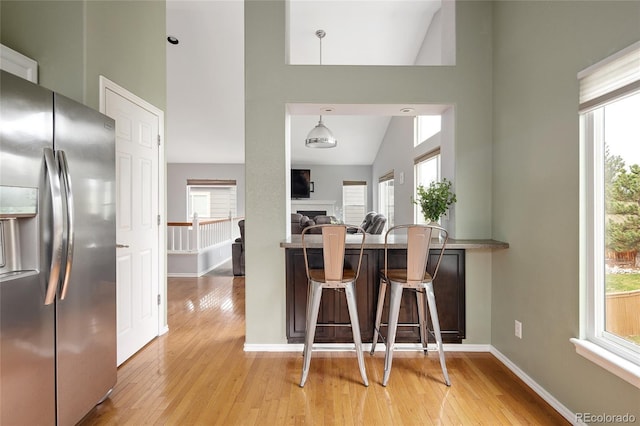kitchen with light wood finished floors, a wealth of natural light, and stainless steel refrigerator with ice dispenser