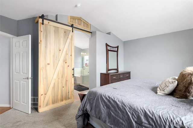 carpeted bedroom with ensuite bath, lofted ceiling, and a barn door
