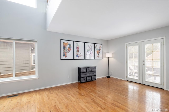 spare room featuring french doors, wood finished floors, baseboards, and visible vents