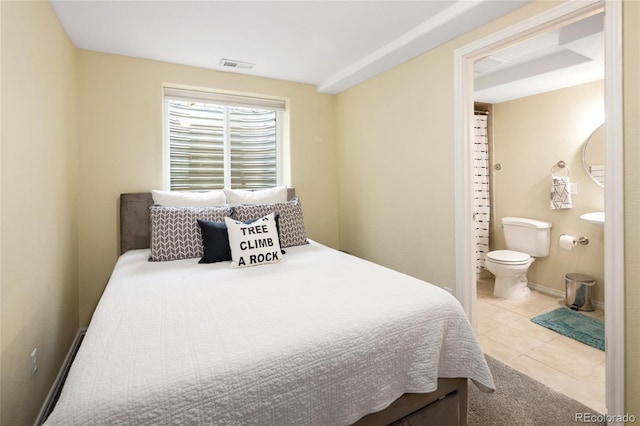 bedroom with tile patterned floors, visible vents, baseboards, and connected bathroom