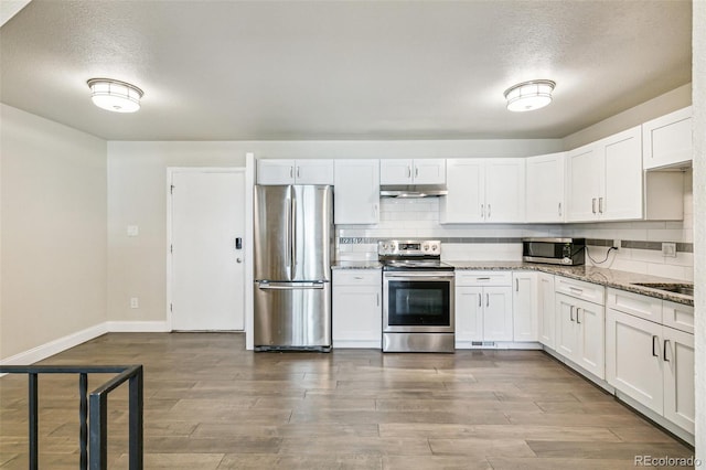 12020 E Canal Dr, Aurora, CO 80011 - kitchen featuring stainless steel appliances, under cabinet range hood, a textured ceiling, white cabinets, and tasteful backsplash