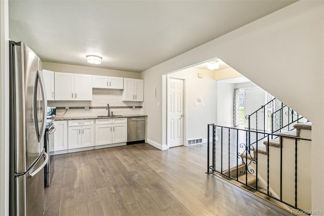 12020 E Canal Dr, Aurora, CO 80011 - kitchen with stainless steel appliances, a sink, wood finished floors, white cabinets, and baseboards