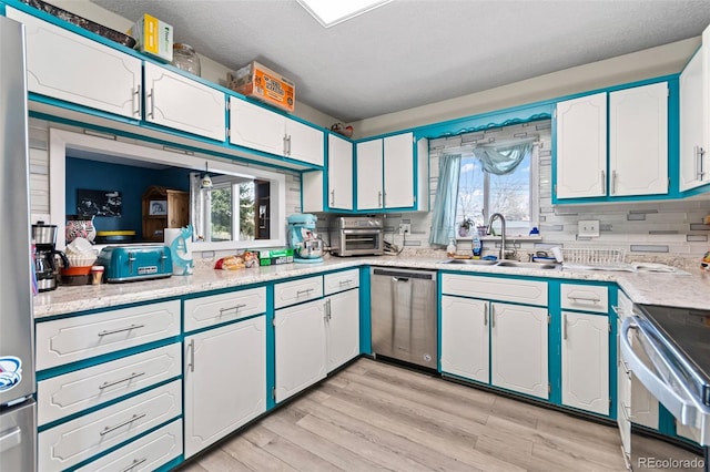 kitchen with white cabinetry, appliances with stainless steel finishes, light countertops, and a sink