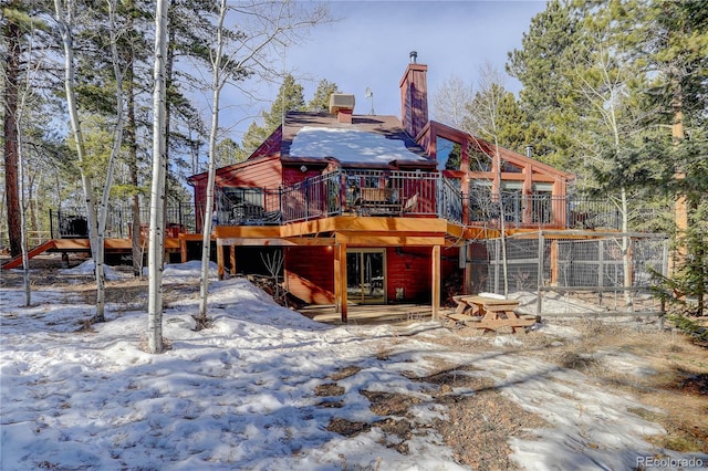 snow covered rear of property with a deck