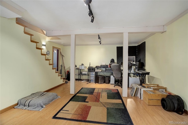 basement with rail lighting, hardwood / wood-style flooring, and crown molding