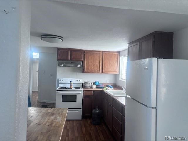 310 E Strong Ave, Trinidad, CO 81082 - kitchen featuring white appliances, under cabinet range hood, dark wood-type flooring, and light countertops