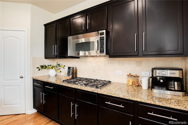 3027 Walnut Grove St, Erie, CO 80516 - kitchen with appliances with stainless steel finishes, light stone countertops, backsplash, and light wood-type flooring