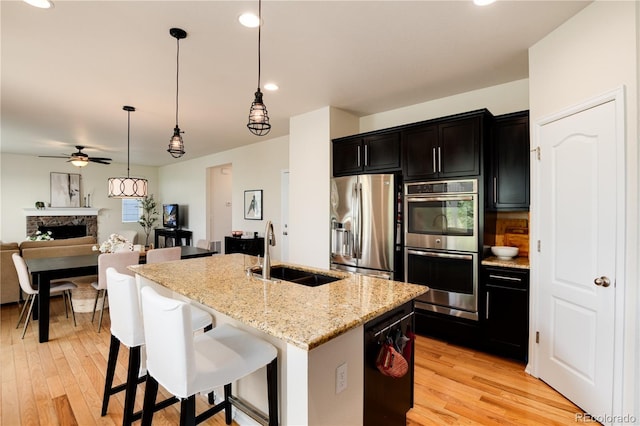 3027 Walnut Grove St, Erie, CO 80516 - kitchen with stainless steel appliances, ceiling fan, light wood finished floors, a kitchen island with sink, and recessed lighting