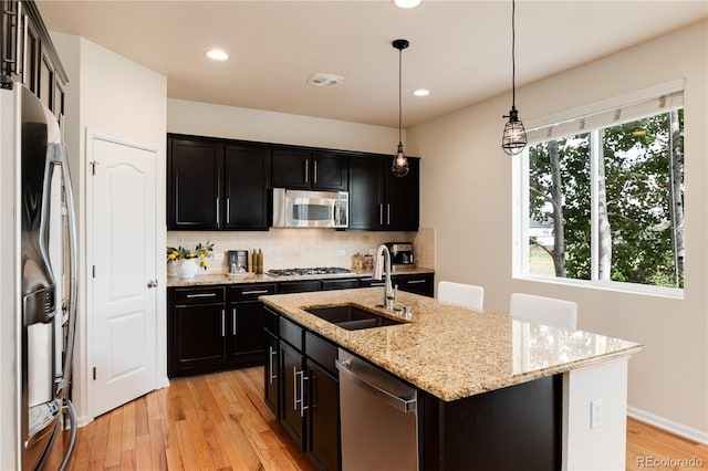 3027 Walnut Grove St, Erie, CO 80516 - kitchen with appliances with stainless steel finishes, light wood finished floors, tasteful backsplash, recessed lighting, and a kitchen island with sink