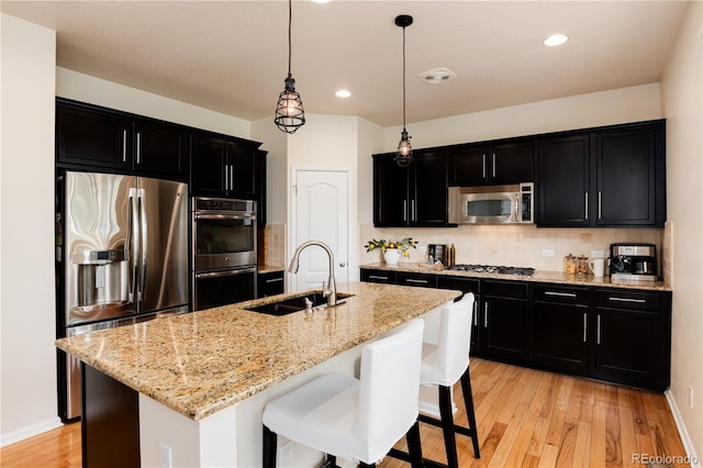 3027 Walnut Grove St, Erie, CO 80516 - kitchen featuring stainless steel appliances, dark cabinetry, decorative backsplash, light wood finished floors, and recessed lighting