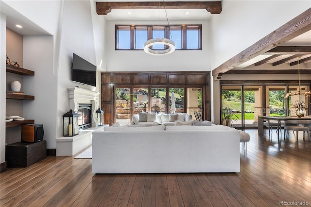 living room with a high ceiling, beam ceiling, dark hardwood / wood-style floors, and a chandelier