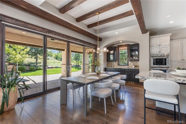 dining area with a healthy amount of sunlight, beam ceiling, and dark hardwood / wood-style floors