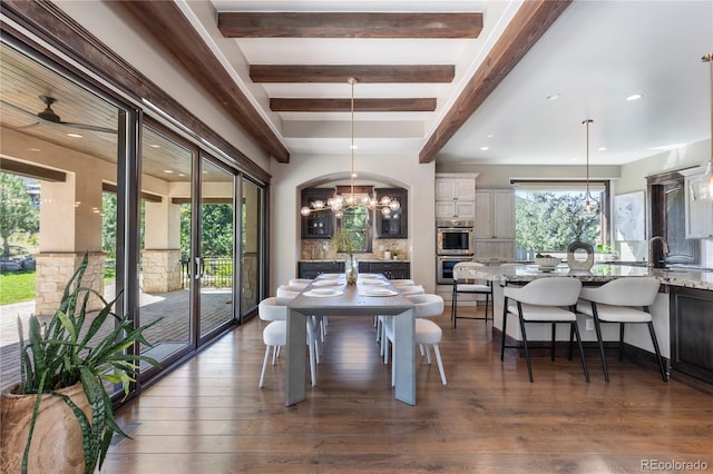 dining area featuring ceiling fan with notable chandelier, beam ceiling, dark wood-type flooring, and sink