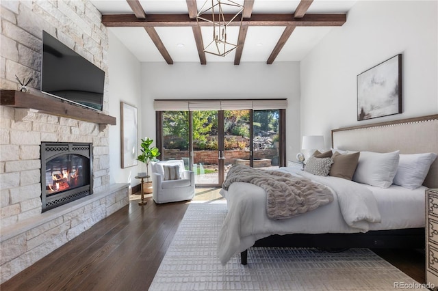 bedroom with a stone fireplace, dark wood-type flooring, and beamed ceiling