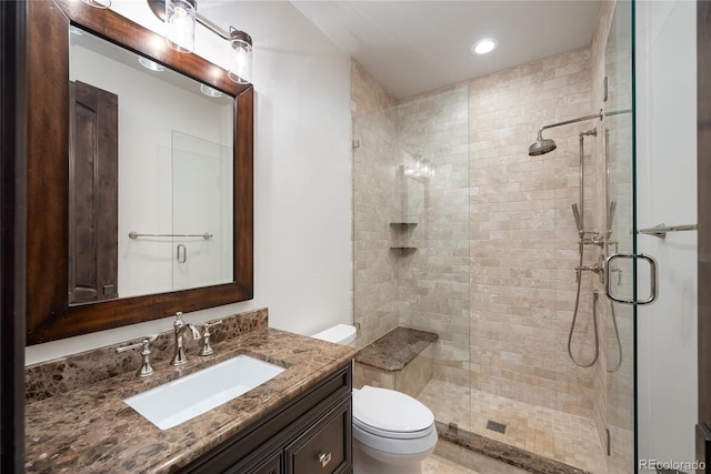 bathroom with a shower with door, vanity, and toilet