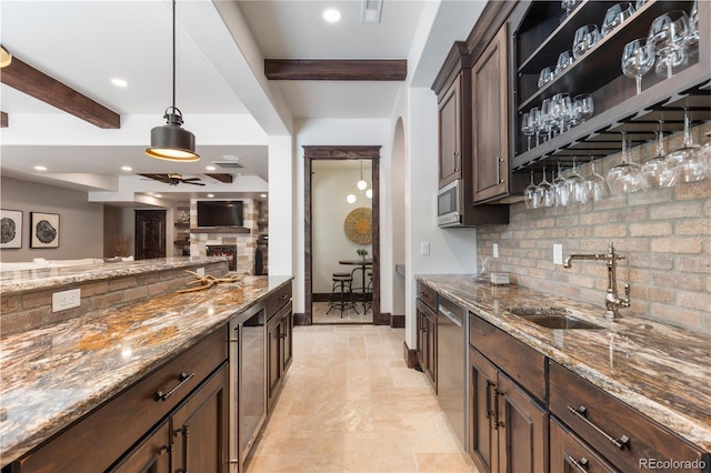 kitchen with pendant lighting, light stone counters, sink, beam ceiling, and decorative backsplash