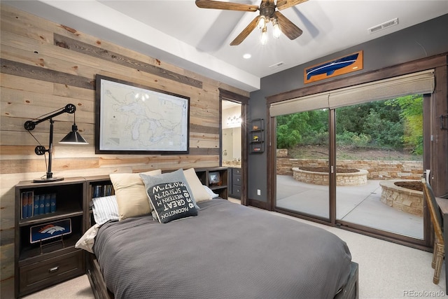 carpeted bedroom with wood walls, ceiling fan, and access to outside