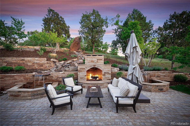 patio terrace at dusk featuring an outdoor stone fireplace