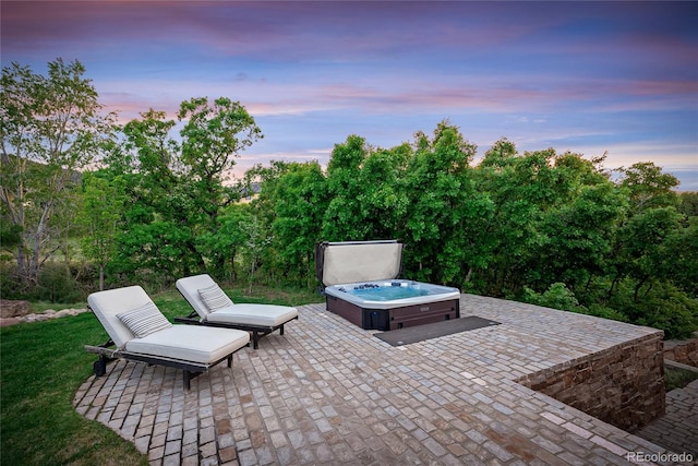 patio terrace at dusk featuring a hot tub