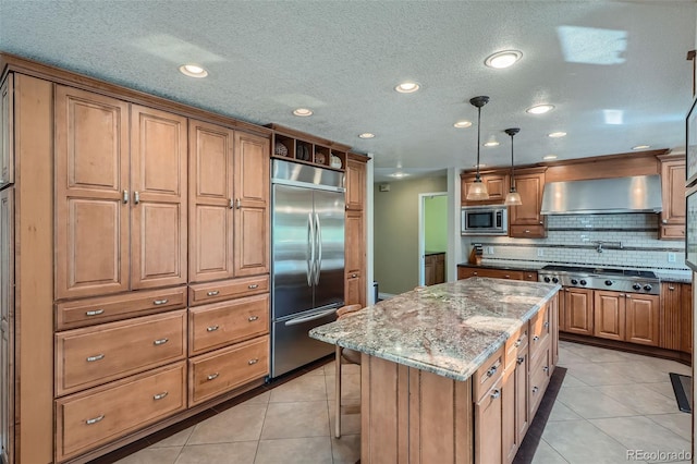 kitchen featuring hanging light fixtures, a kitchen island, built in appliances, and light tile patterned floors