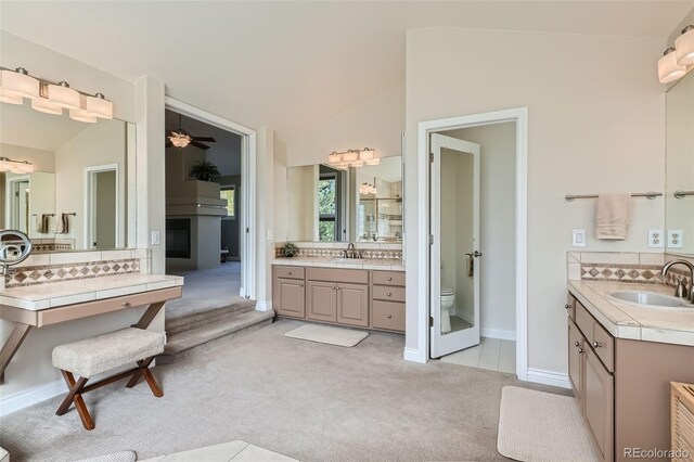 bathroom featuring lofted ceiling, ceiling fan, vanity, and toilet