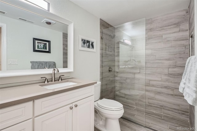 bathroom featuring toilet, vanity, and a shower with shower door