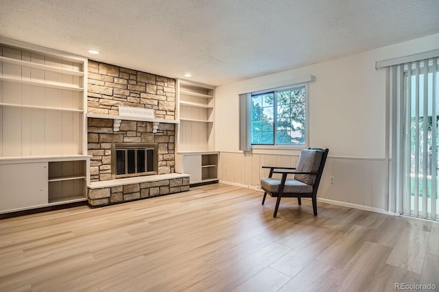 2514 S Elkhart St, Aurora, CO 80014 - unfurnished room featuring a textured ceiling, built in shelves, wood finished floors, wainscoting, and a stone fireplace