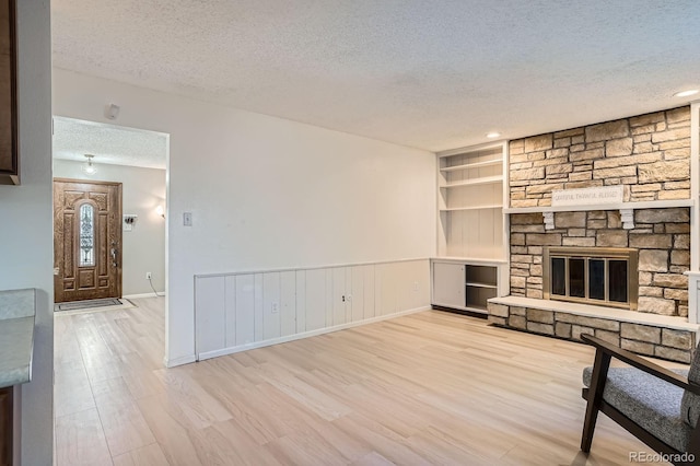 2514 S Elkhart St, Aurora, CO 80014 - unfurnished living room with a textured ceiling, wood finished floors, built in shelves, and a fireplace