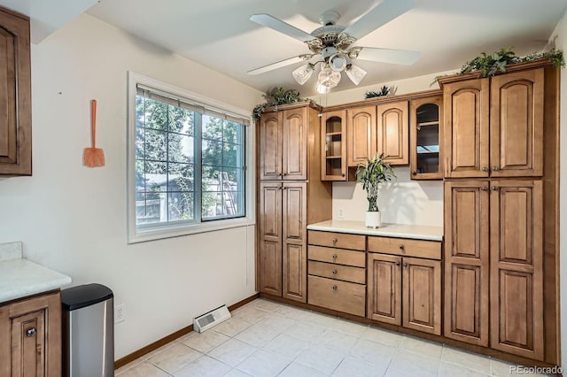2514 S Elkhart St, Aurora, CO 80014 - kitchen with brown cabinets, a ceiling fan, and glass insert cabinets
