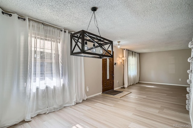 2514 S Elkhart St, Aurora, CO 80014 - unfurnished dining area featuring wood finished floors, a textured ceiling, and a chandelier