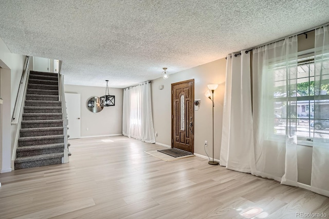 2514 S Elkhart St, Aurora, CO 80014 - foyer entrance featuring a textured ceiling, light wood-style floors, stairs, and a chandelier