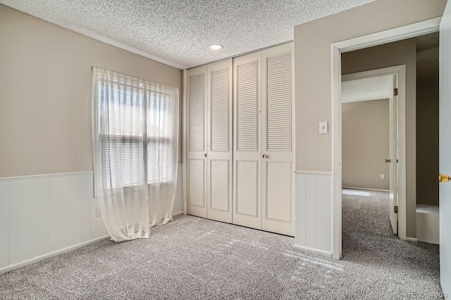 2514 S Elkhart St, Aurora, CO 80014 - unfurnished bedroom with carpet, a textured ceiling, a wainscoted wall, a closet, and a decorative wall