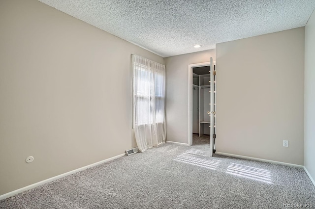 2514 S Elkhart St, Aurora, CO 80014 - unfurnished bedroom featuring carpet flooring, a textured ceiling, and a walk in closet