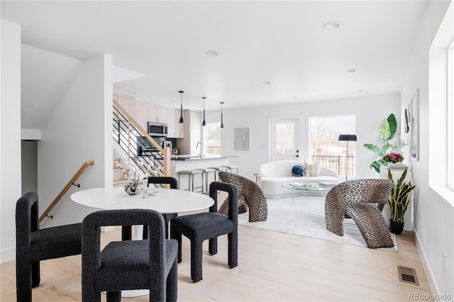 dining room featuring visible vents, baseboards, light wood-style flooring, stairway, and recessed lighting